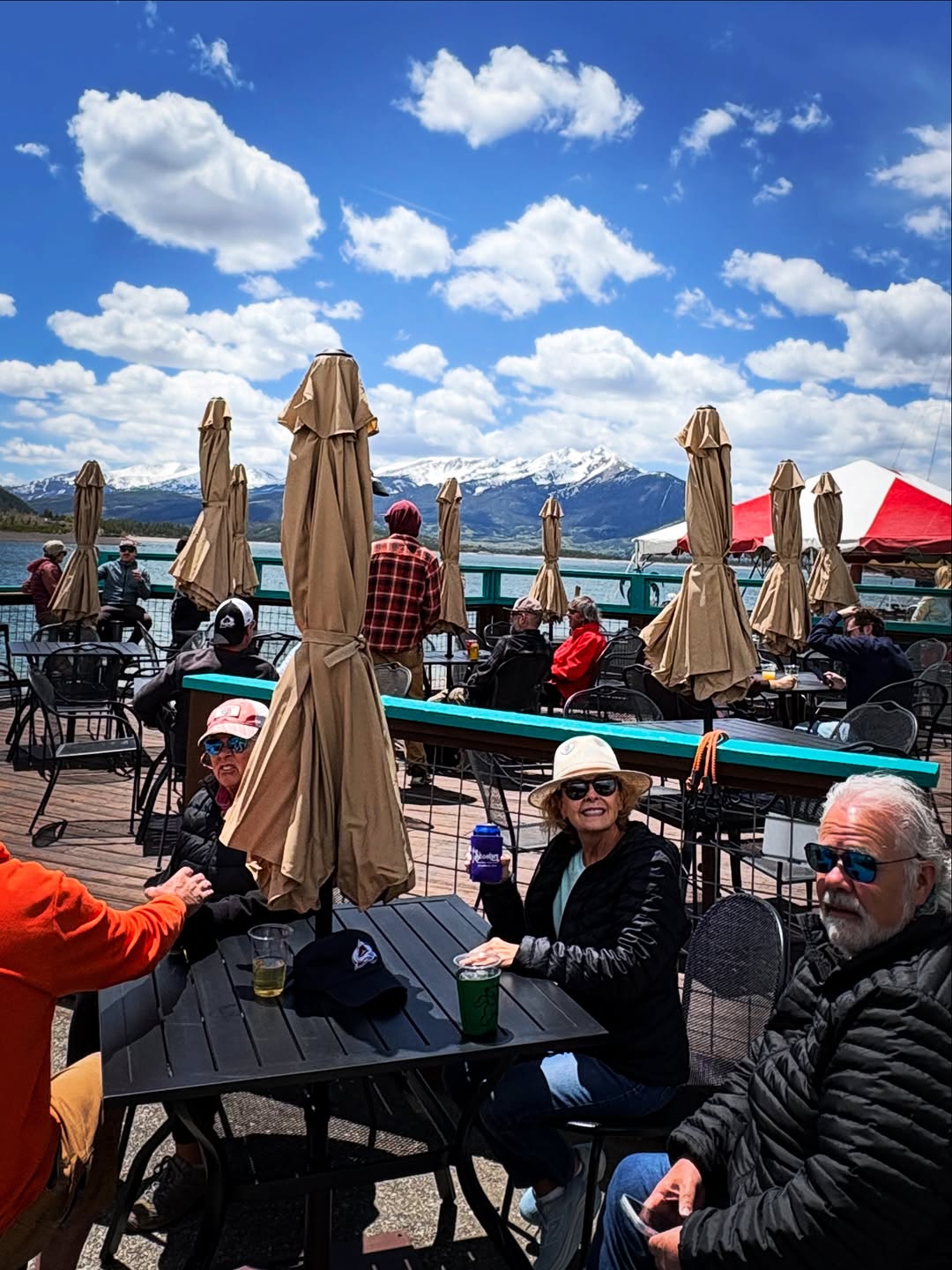 The Steep deck under umbrellas, packed with guests, snowy mountains across Lake Dillon.